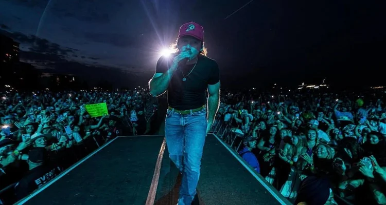 Wearing Morgan Wallen trucker hat outdoor concert festival